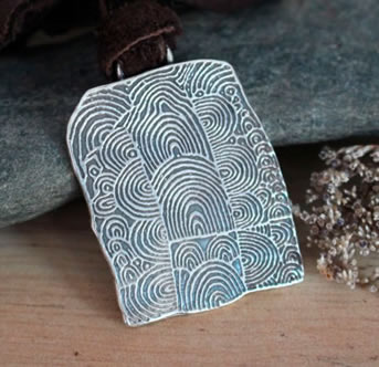 Dije Cairn de Gavrinis que representa una de las piedras esculpidas con espirales.