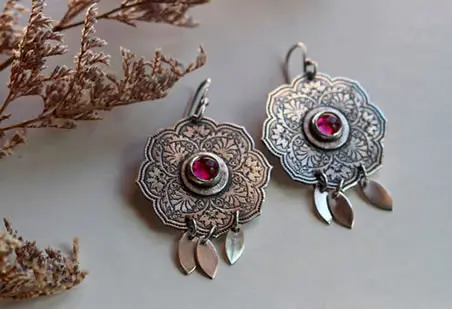 Aretes La Rosa de Oriente que evocan la flor a través de su delicado grabado y su rubí rosa.