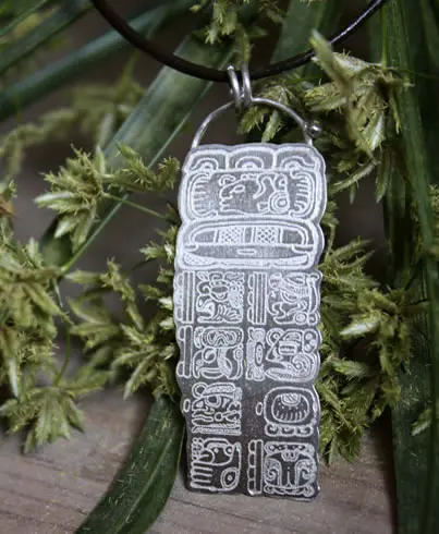 Dije con el calendario maya que muestra una fecha calculada según la Cuenta Larga.
