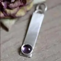 Dije rectangular de plata y piedra de nacimiento.