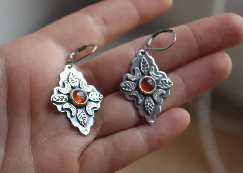 Farándula bajo la luna naranja, aretes de hojas y lunas en plata y cornalina