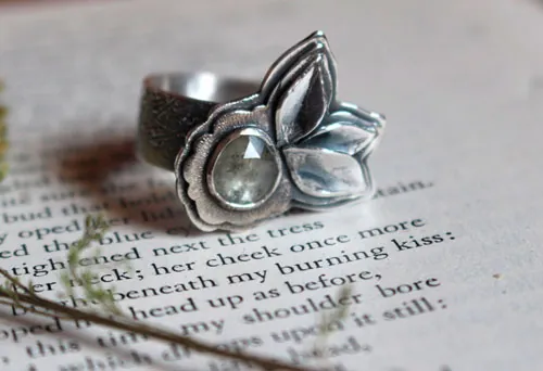 Florecer bajo el universo, anillo flor y pétalos en plata y zafiro transparente