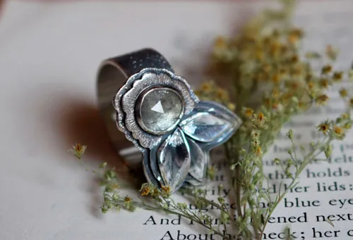Florecer bajo el universo, anillo flor y pétalos en plata y zafiro transparente