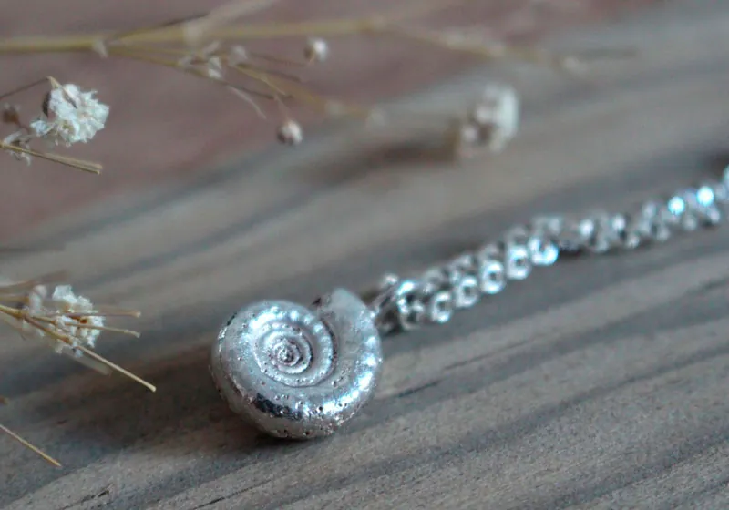 La cuna de la vida, collar náutilo Ammonita con piedra de nacimiento en plata y rubí