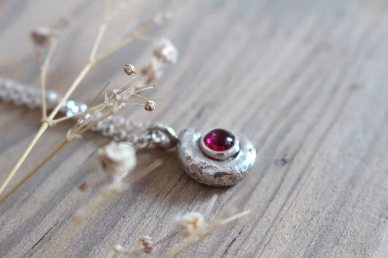 La cuna de la vida, collar náutilo Ammonita con piedra de nacimiento en plata y rubí