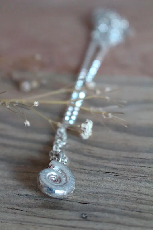 La cuna de la vida, collar náutilo Ammonita con piedra de nacimiento en plata y rubí