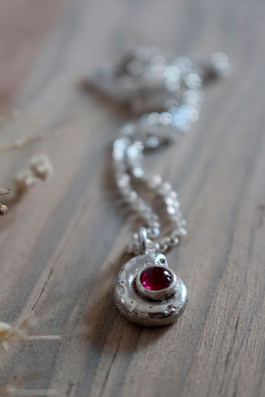 La cuna de la vida, collar náutilo Ammonita con piedra de nacimiento en plata y rubí