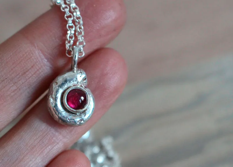 La cuna de la vida, collar náutilo Ammonita con piedra de nacimiento en plata y rubí