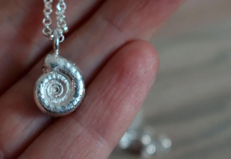 La cuna de la vida, collar náutilo Ammonita con piedra de nacimiento en plata y rubí