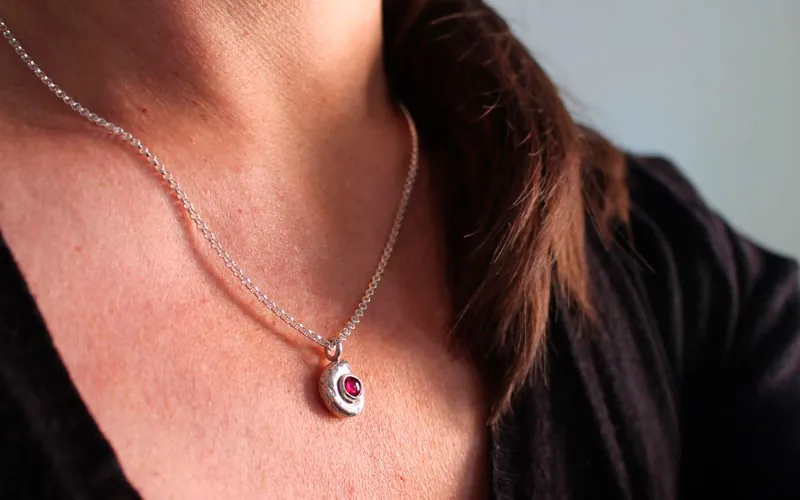 La cuna de la vida, collar náutilo Ammonita con piedra de nacimiento en plata y rubí