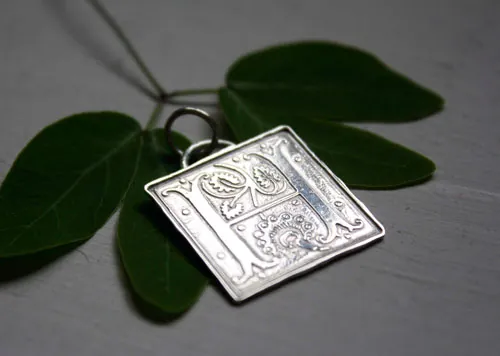 Letra capitular, dije inicial con iluminación medieval en plata
